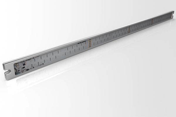 Ein langes Metalllineal oder eine Stahlkante mit gleichmäßig verteilten Markierungen, diagonal auf weißem Hintergrund dargestellt.
