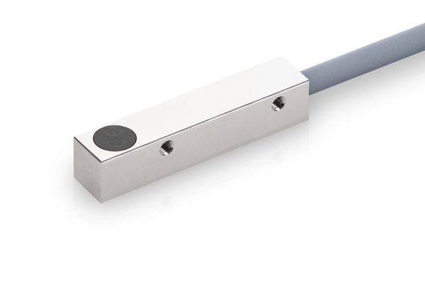 Nahaufnahme eines rechteckigen Metall-Lastsensors mit schwarzer runder Kappe und angekabeltem Kabel auf weißem Hintergrund.