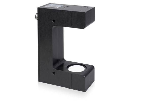 Schwarzer C-förmiger Industrie-Sensor oder Montagebügel mit kreisförmiger Öffnung am unteren Arm, gezeigt auf weißem Hintergrund.