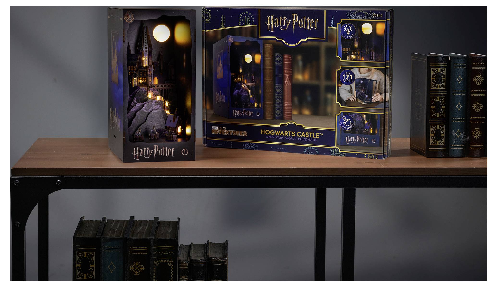 Harry Potter Hogwarts-Schloss Sammlerset in Boxen auf einem Regal ausgestellt, mit leuchtendem Schloss-Artwork und einem verpackten Zugmodell.
