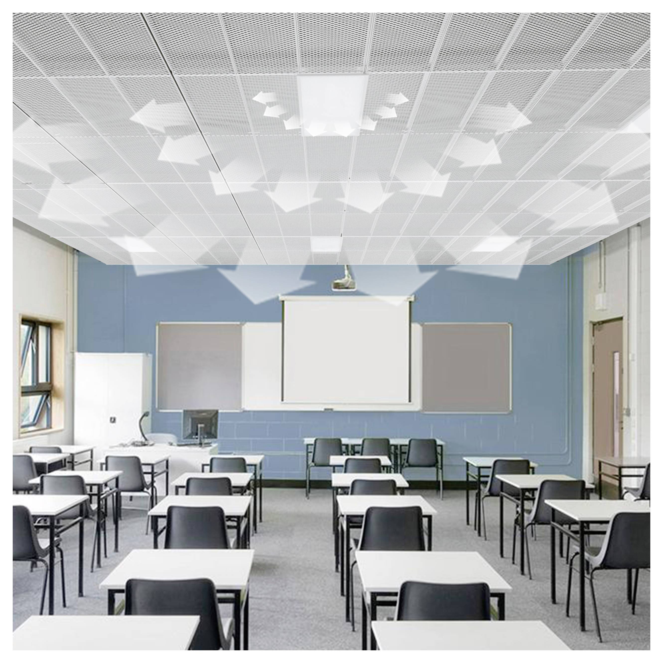 Leeres Klassenzimmer mit Reihen von Schreibtischen und Stühlen, die auf eine Projektionsleinwand an einer blauen Wand ausgerichtet sind, beleuchtet durch Deckenleuchten und Fenster.
