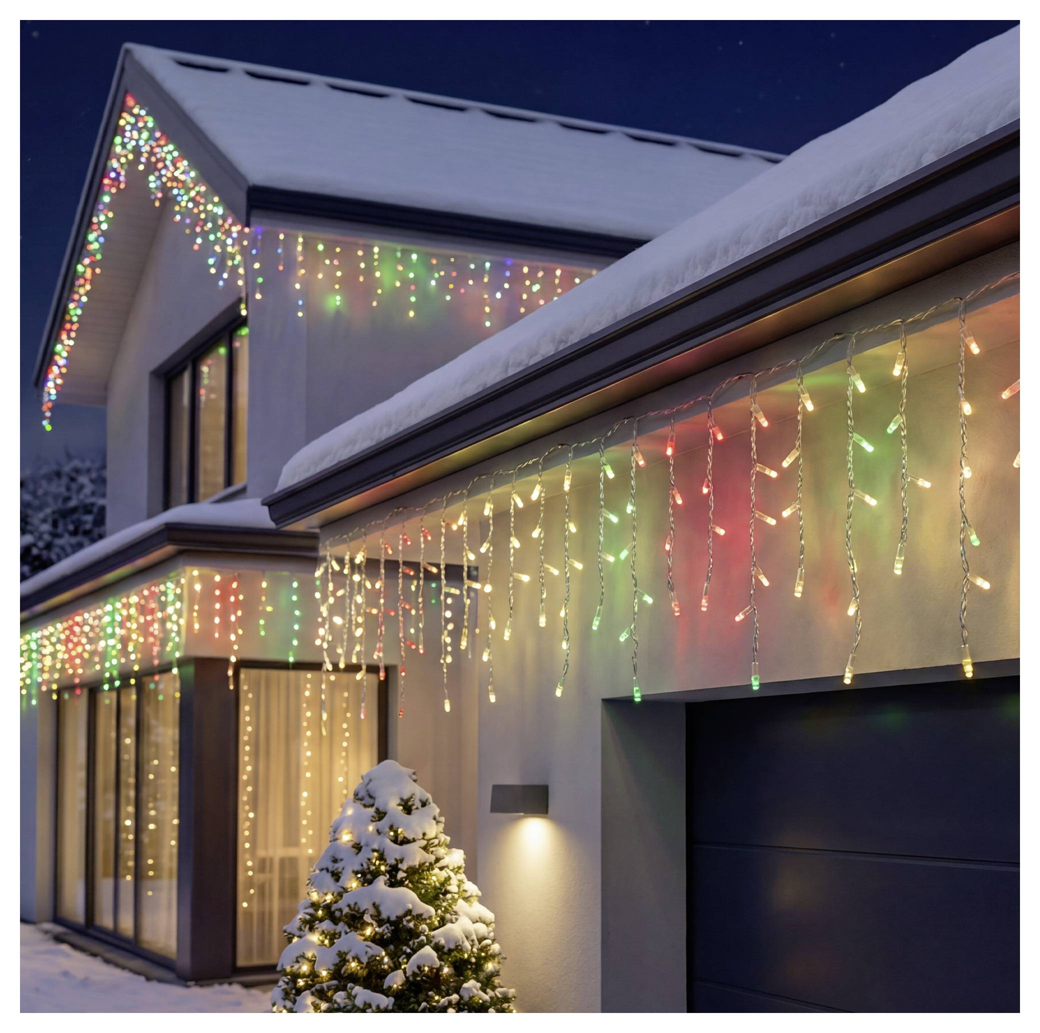 Schneebedecktes Haus, das mit farbenfrohen Weihnachtslichtern und Eiszapfen-Lichterketten dekoriert ist, mit einem beleuchteten Außenbaum neben der Garage in der Nacht.