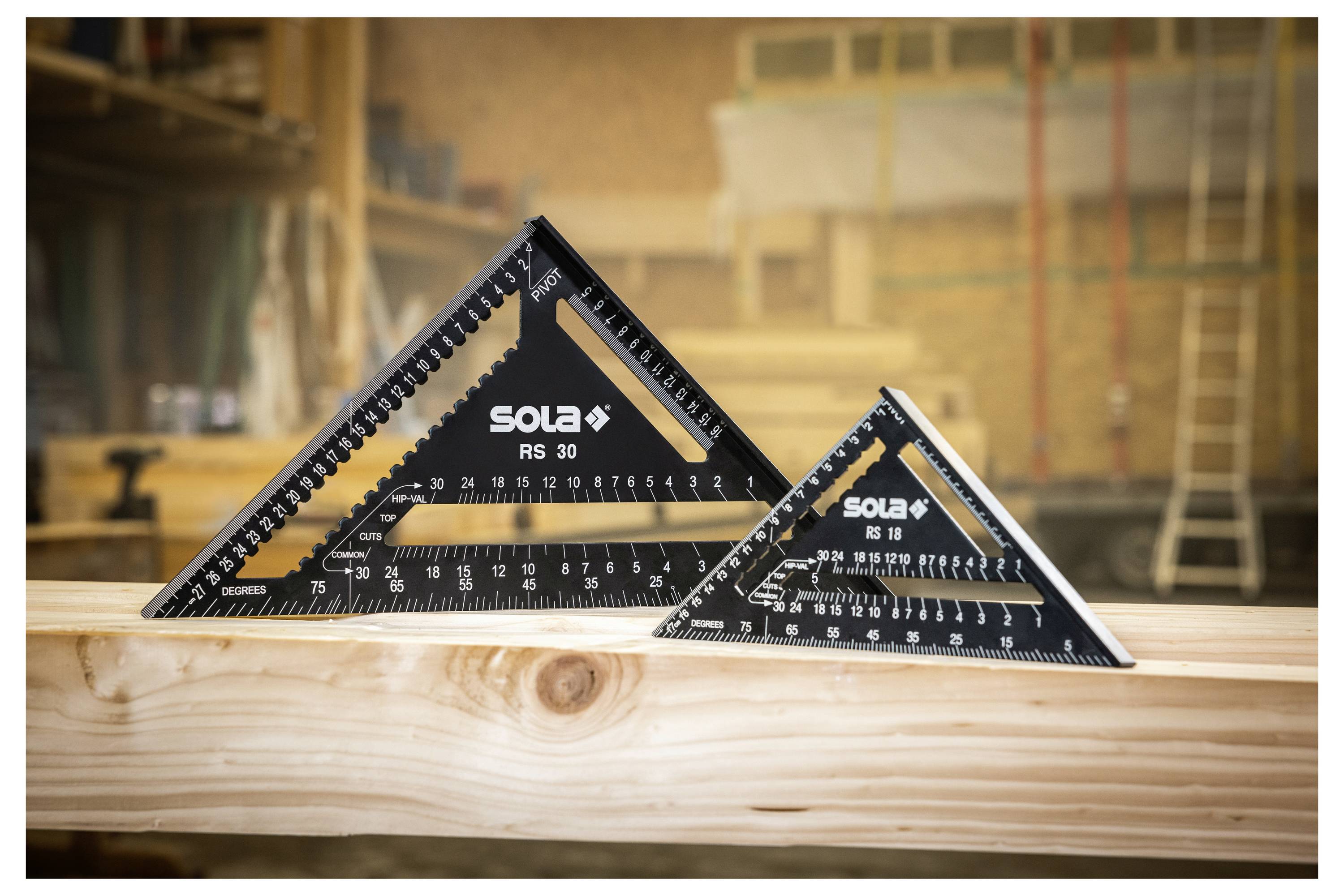 Zwei schwarze dreieckige Zimmermannswinkel mit der Aufschrift „SOLA