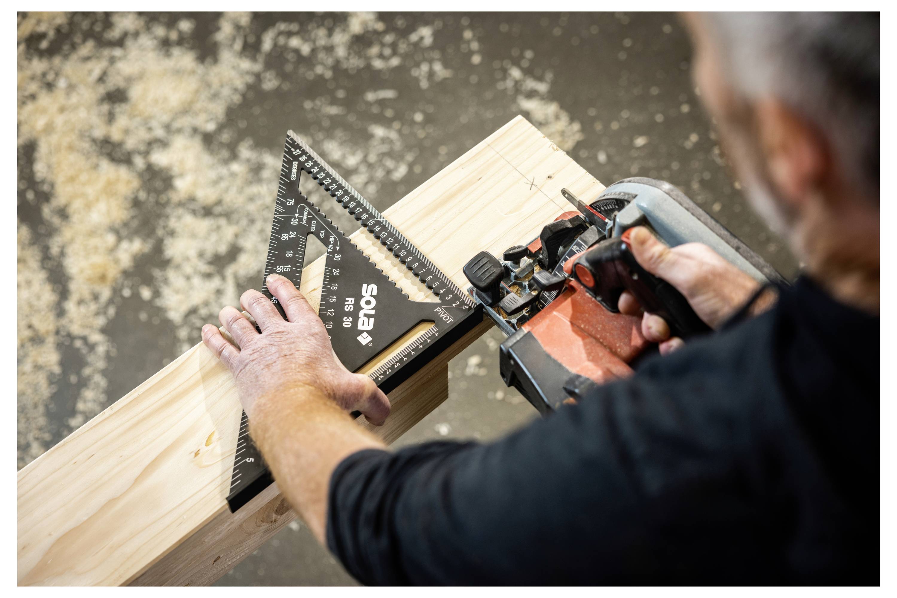 Person, der eine Elektrosäge und ein Winkel verwendet, um einen Holzbalken auf einer Werkbank genau zu schneiden.