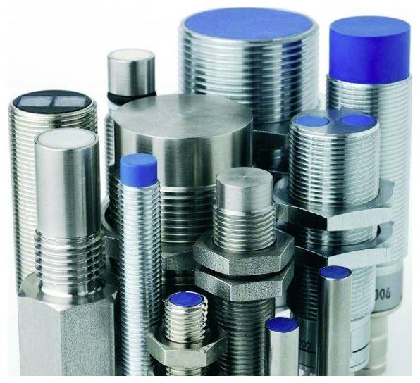 Verschiedene Metallbolzen, Schrauben und Gewindebefestigungselemente mit blauen Schutzdeckeln, aufrecht auf weißem Hintergrund angeordnet.
