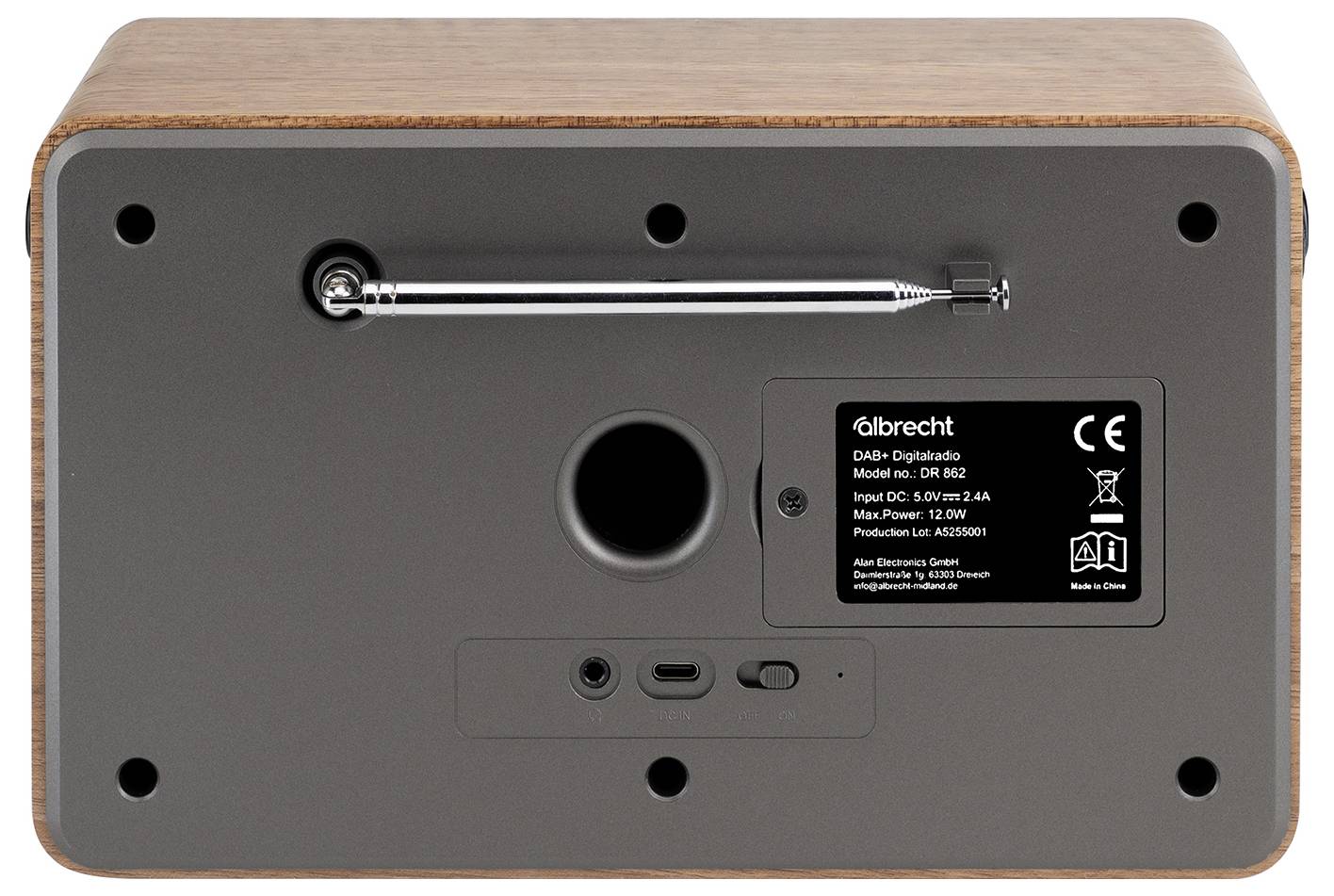 Unteransicht eines tragbaren Lautsprechers mit Holzgehäuse, die einen Metalltragegriff, Gummifüße, Anschlüsse und ein Produktetikett zeigt.