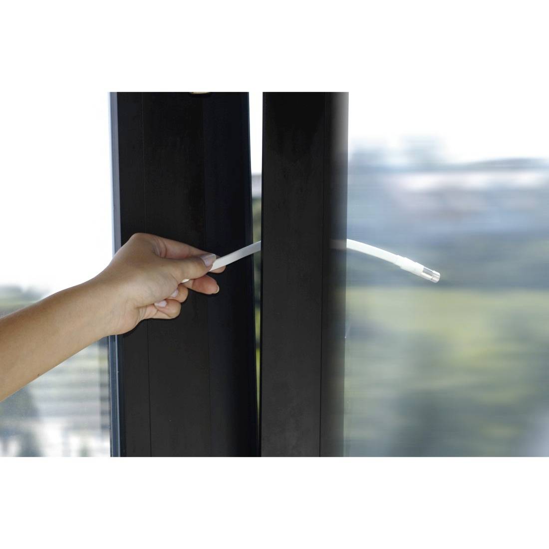 Hand, die einen Fenstergriff an einem schwarzgerahmten Glasfenster öffnet, mit unscharfem Außenblick dahinter.