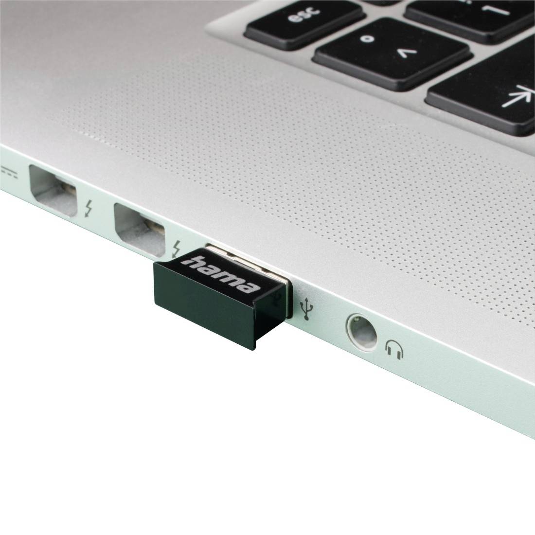 Nahaufnahme einer Laptop-Kante mit einem eingesteckten Hama-USB-Gerät neben Ethernet-, Strom- und Kopfhörerbuchsen.
