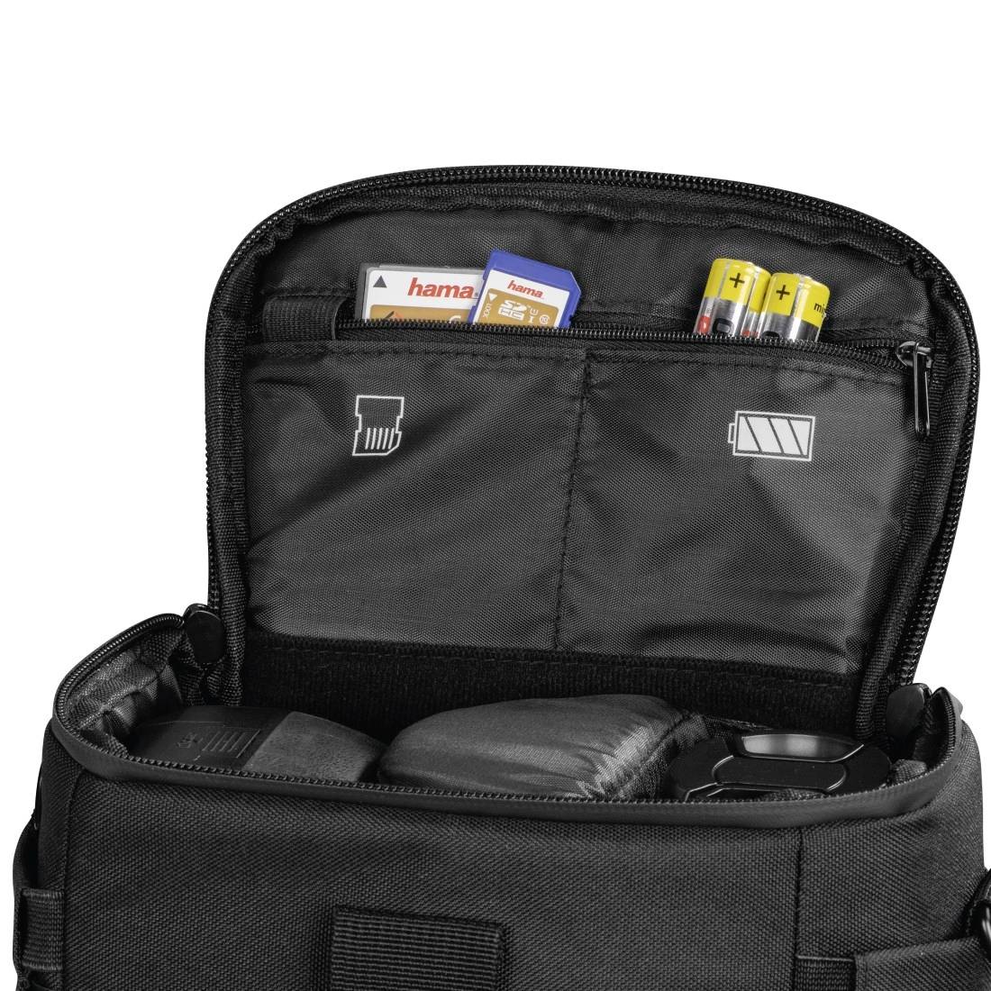 Offener schwarzer Transportkoffer mit organisierten Fächern, die Speicherkarten, Batterien und Zubehör auf weißem Hintergrund enthält.