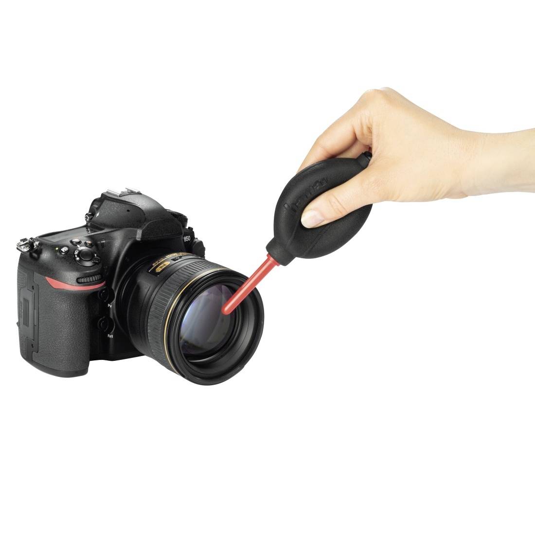 Handreinigung des Kameraobjektivs mit einem Gebläse an einer DSLR-Kamera.