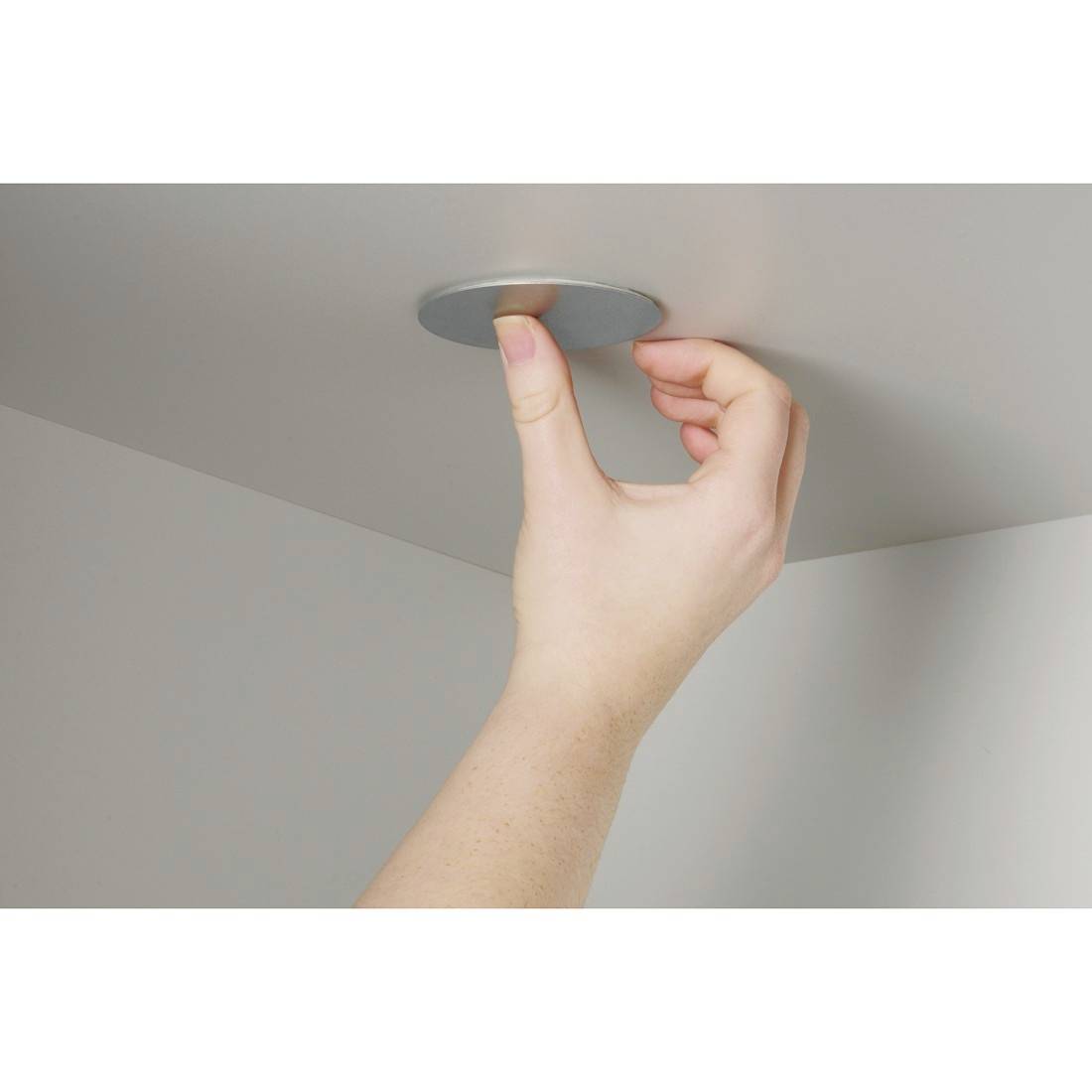 Eine Hand drückt ein vertieftes Deckenleuchte oder Sensor in ein Deckenpaneel.