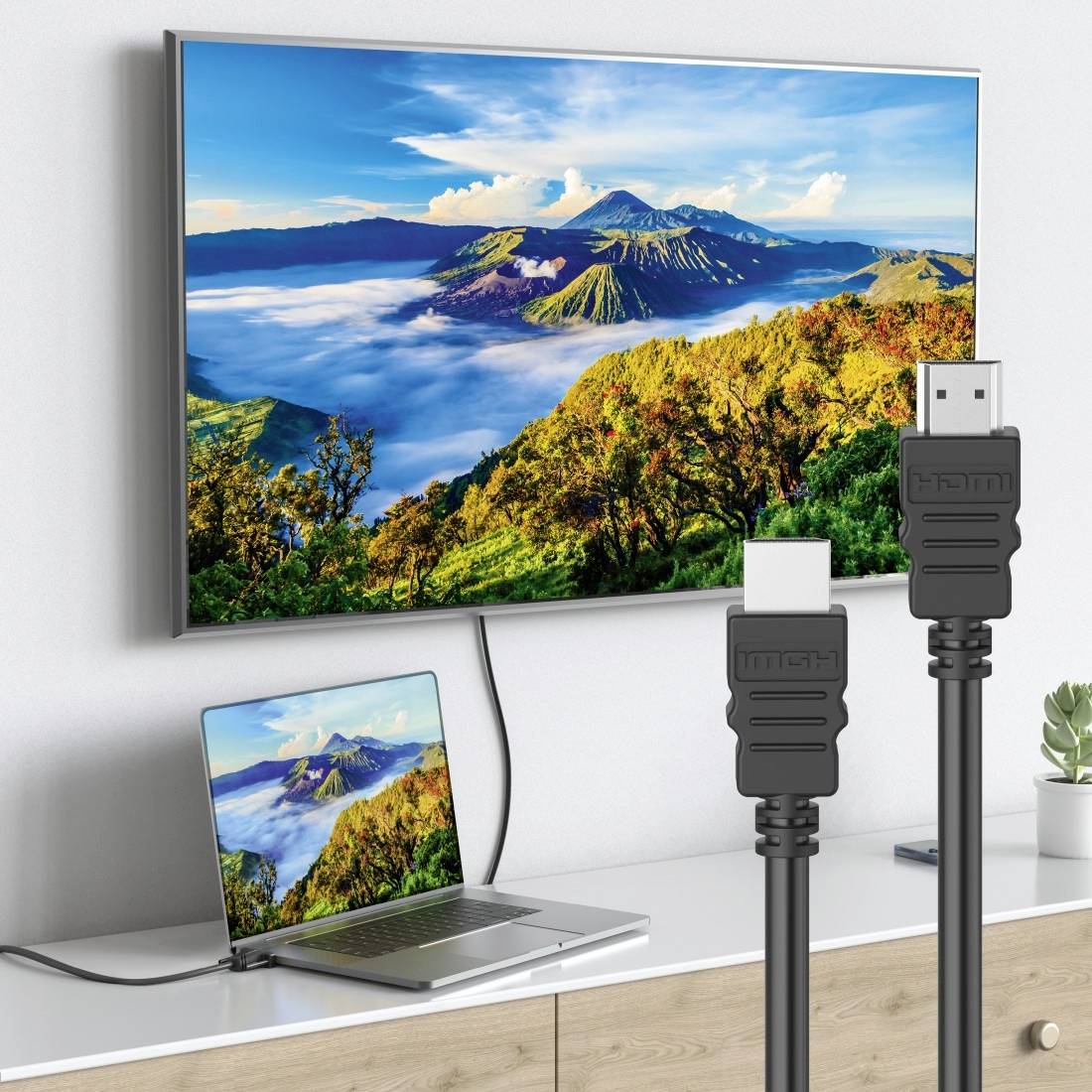 Laptop über HDMI-Kabel mit Wandfernseher verbunden, spiegelt eine Berglandschaft auf beiden Bildschirmen.