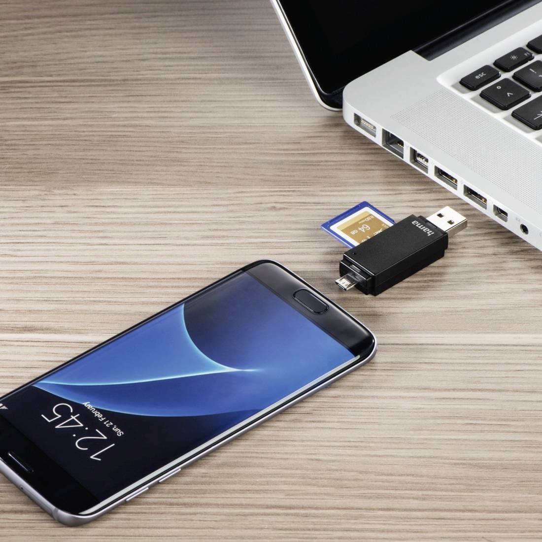 Smartphone, USB-Stick und Speicherkarte neben einem Laptop, was auf Dateiübertragung oder Gerätesicherung hindeutet.