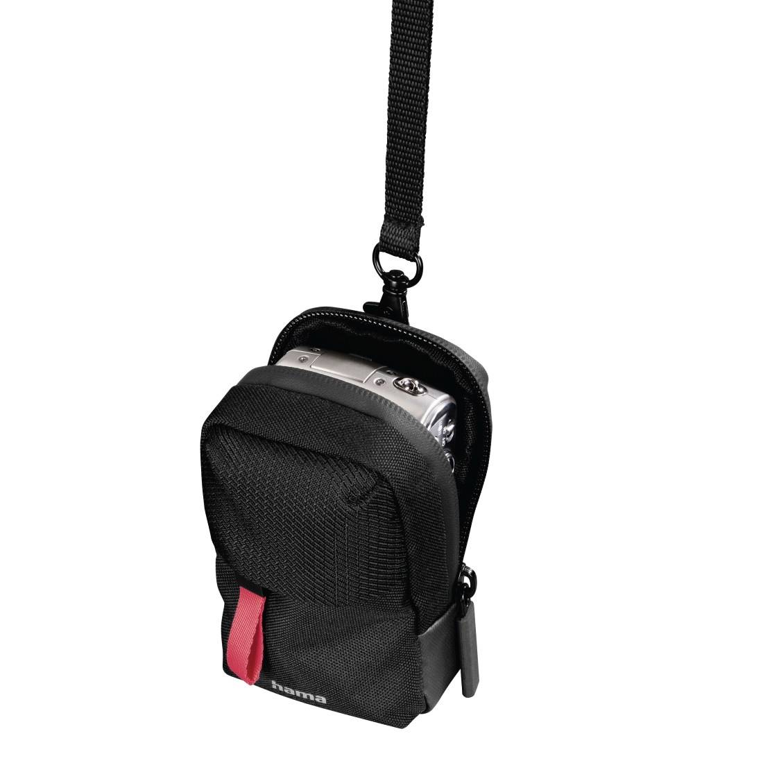 Schwarze kompakte Kameratasche mit Schultergurt, in deren offener Vordertasche eine silberne Digitalkamera sitzt.