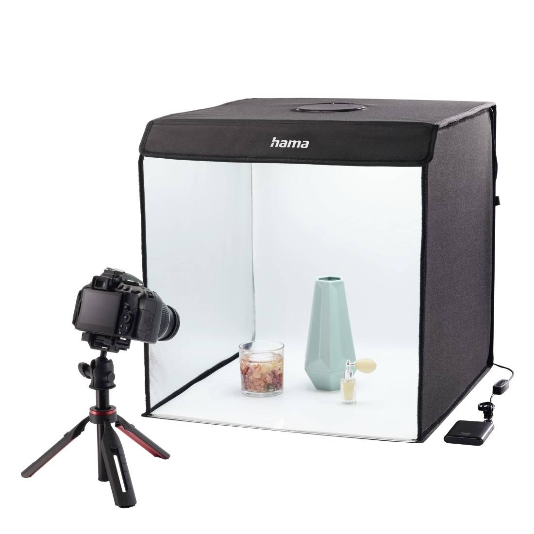 Kamera auf Stativ fotografiert ein Produkt in einem kleinen weißen Lightbox-Studio mit einem „Hama