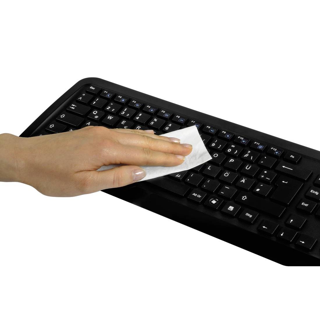 Eine Hand wischt eine schwarze Computertastatur mit einem Tuch auf weißem Hintergrund ab.