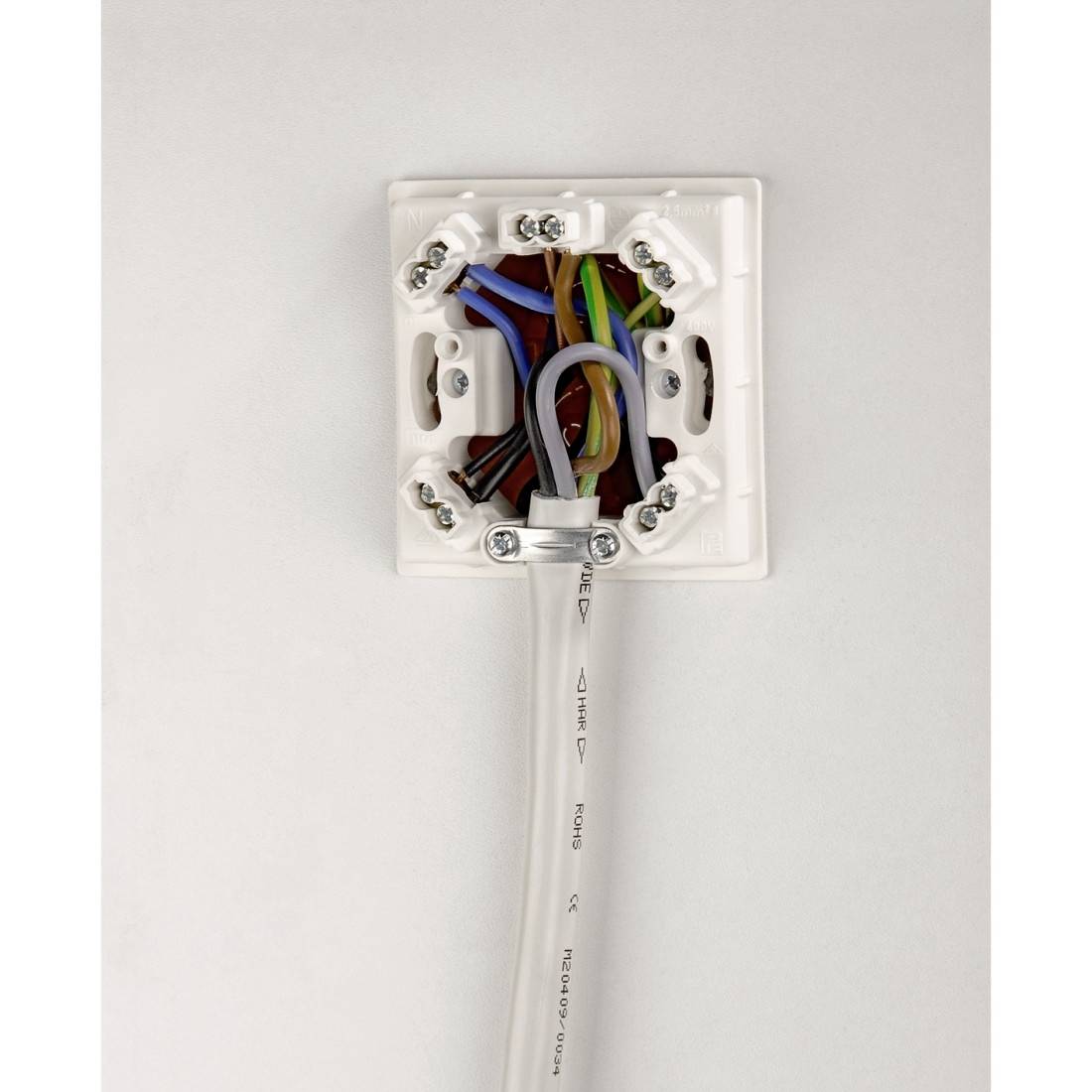 Elektrische Wandsteckdosendose mit freiliegender farbiger Verkabelung und einem weißen Kabel, das von unten eindringt.