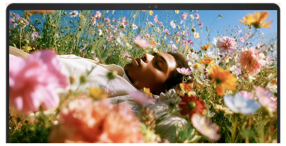 Eine Person liegt in einem farbenfrohen Wildblumenfeld unter einem blauen Himmel, von der Seite zu sehen und wirkt entspannt oder schläft.