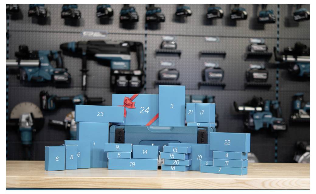 Blau nummerierte Geschenkboxen, wie ein gestapelter Adventskalender auf einem Holztisch angeordnet, mit unscharfen Spielzeugautos, die dahinter ausgestellt sind.