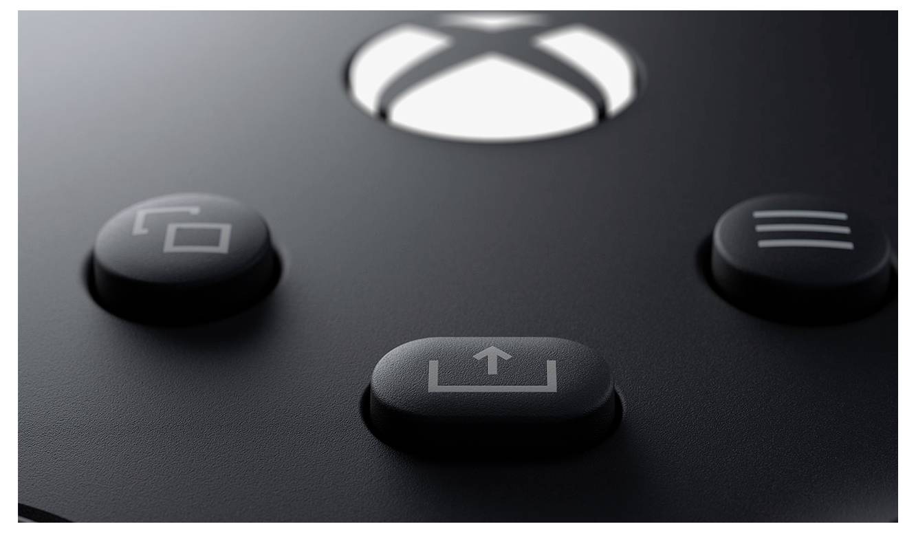 Nahaufnahme von drei schwarzen Xbox-Controller-Tasten, einschließlich einer zentralen Share-Taste mit einem Upload-Symbol, auf einer matten dunklen Oberfläche.