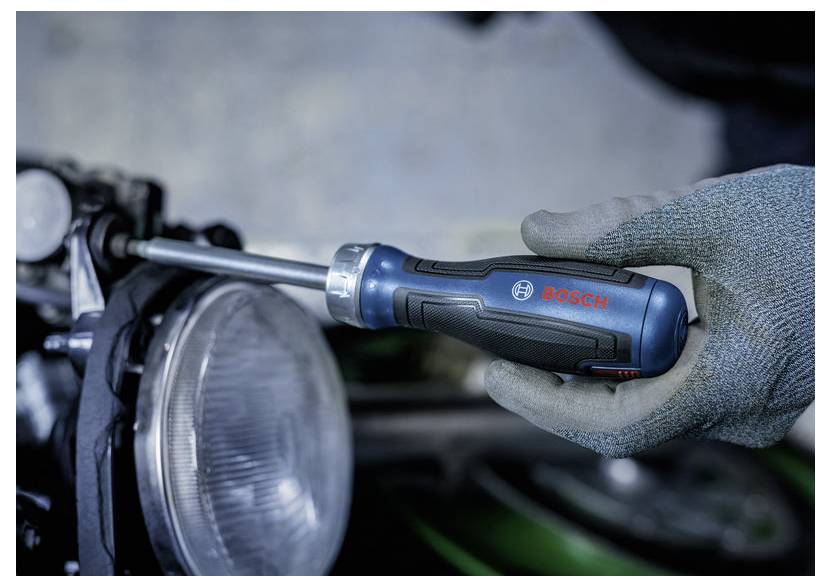 Mit Handschuhen bekleidete Hand, die eine Autokopflampenbaugruppe mit einem Bosch-Schraubendreher festzieht.