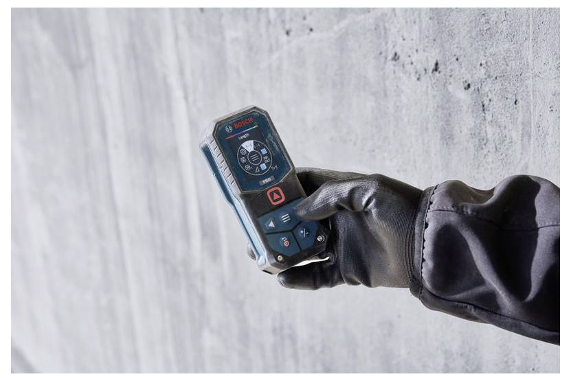 Behandschuhte Hand hält ein Bosch-Laser-Entfernungsmessgerät gegen eine Betonwand, was auf präzise Innenmessungen oder Bauarbeiten hindeutet.