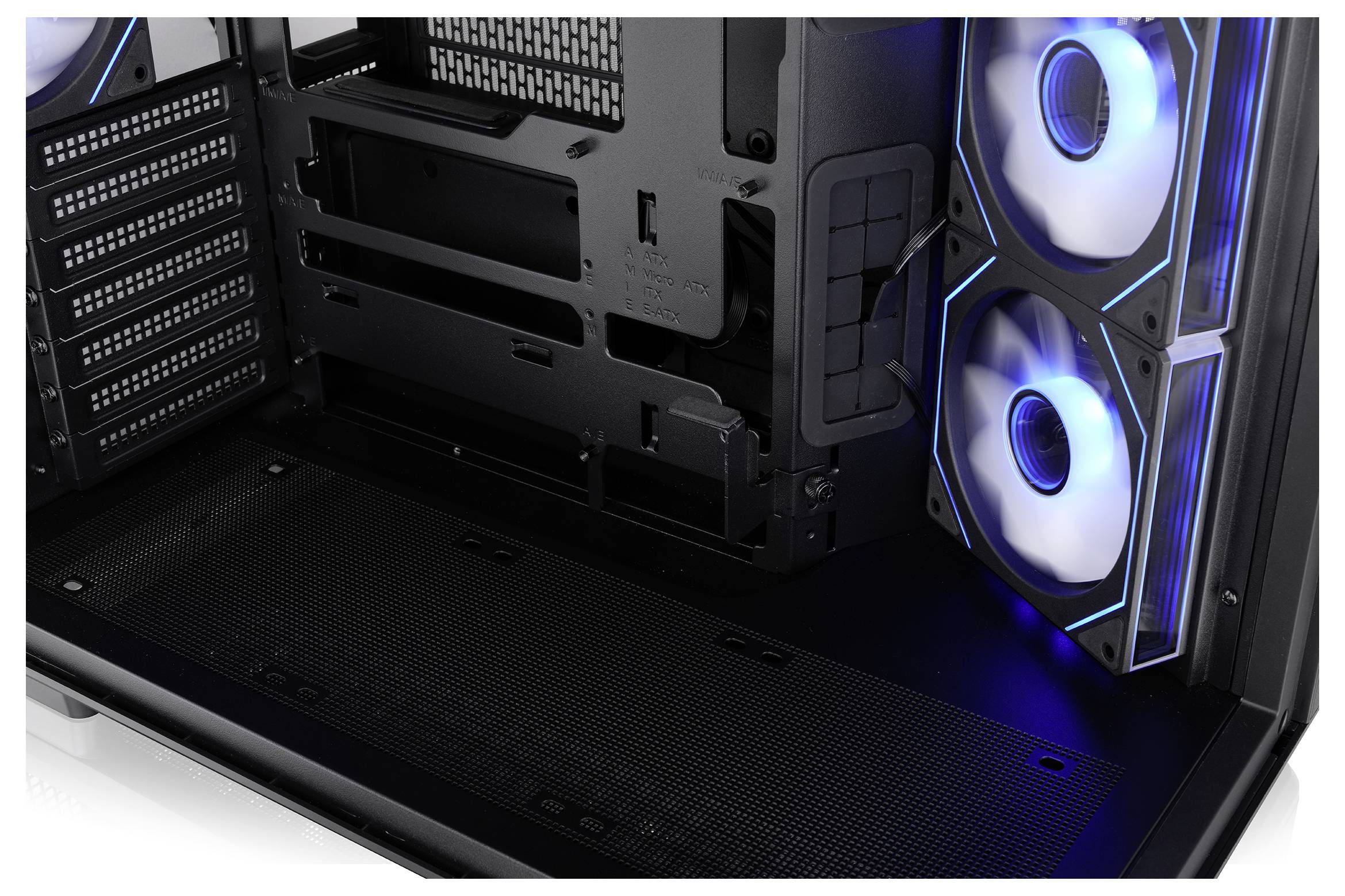Im Inneren eines Desktop-PC-Gehäuses sind zwei blau beleuchtete Kühlungslüfter und ein leeres Motherboard-Tablett mit Kabelführungsbereich in Nahaufnahme zu sehen.