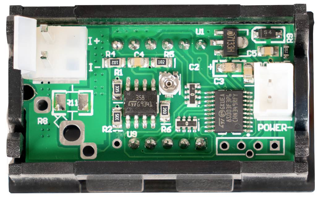Nahaufnahme eines kleinen grünen Leiterplattenmoduls mit zwei weißen Steckern mit der Beschriftung „I+" und „POWER", mehreren integrierten Schaltkreisen, Widerständen und Testpunkten.