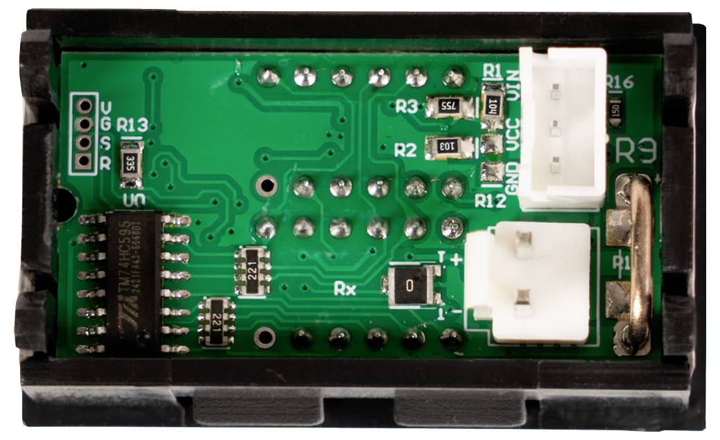 Nahaufnahme eines grünen elektronischen Schaltmoduls in einem schwarzen Gehäuse mit zwei weißen Steckverbindern, beschrifteten Komponenten und sichtbaren Lötstellen.