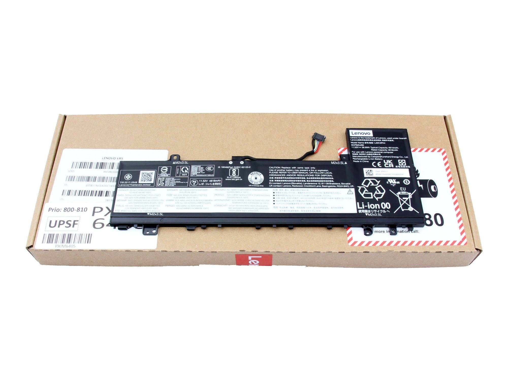 Laptop-Akkupack auf einem Kartonversandkasten ruhend, mit sichtbarem Lenovo-Etikett, Barcodes und Stromanschluss.