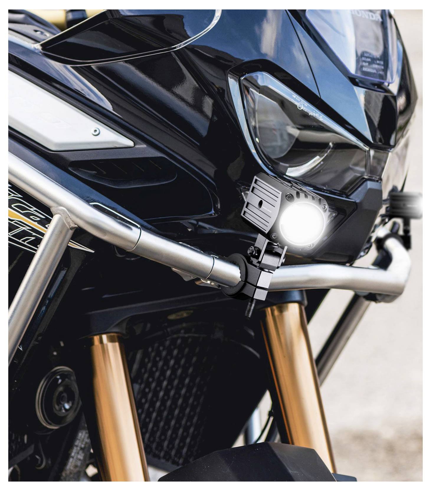 Nahaufnahme einer schwarzen Motorradfront mit leuchtender LED-Scheinwerfer, silbernem Sturzbügel und goldenen Gabeln.