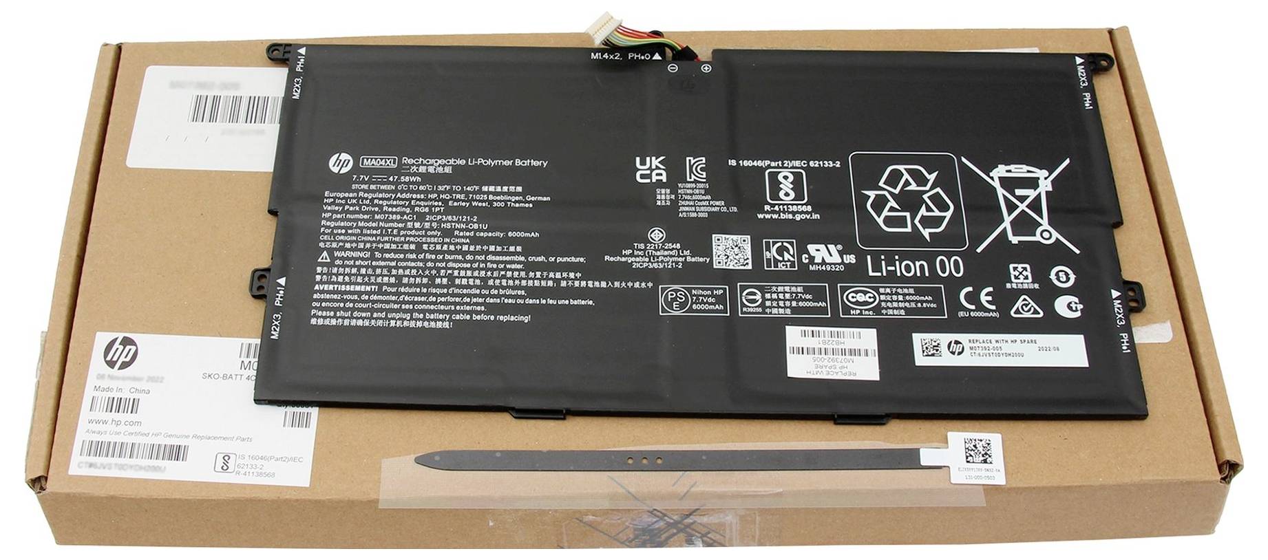 Schwarzes Laptop-Akku-Pack auf einem HP-Kartonversandkarton platziert, mit sichtbaren Etiketten und Barcodes.