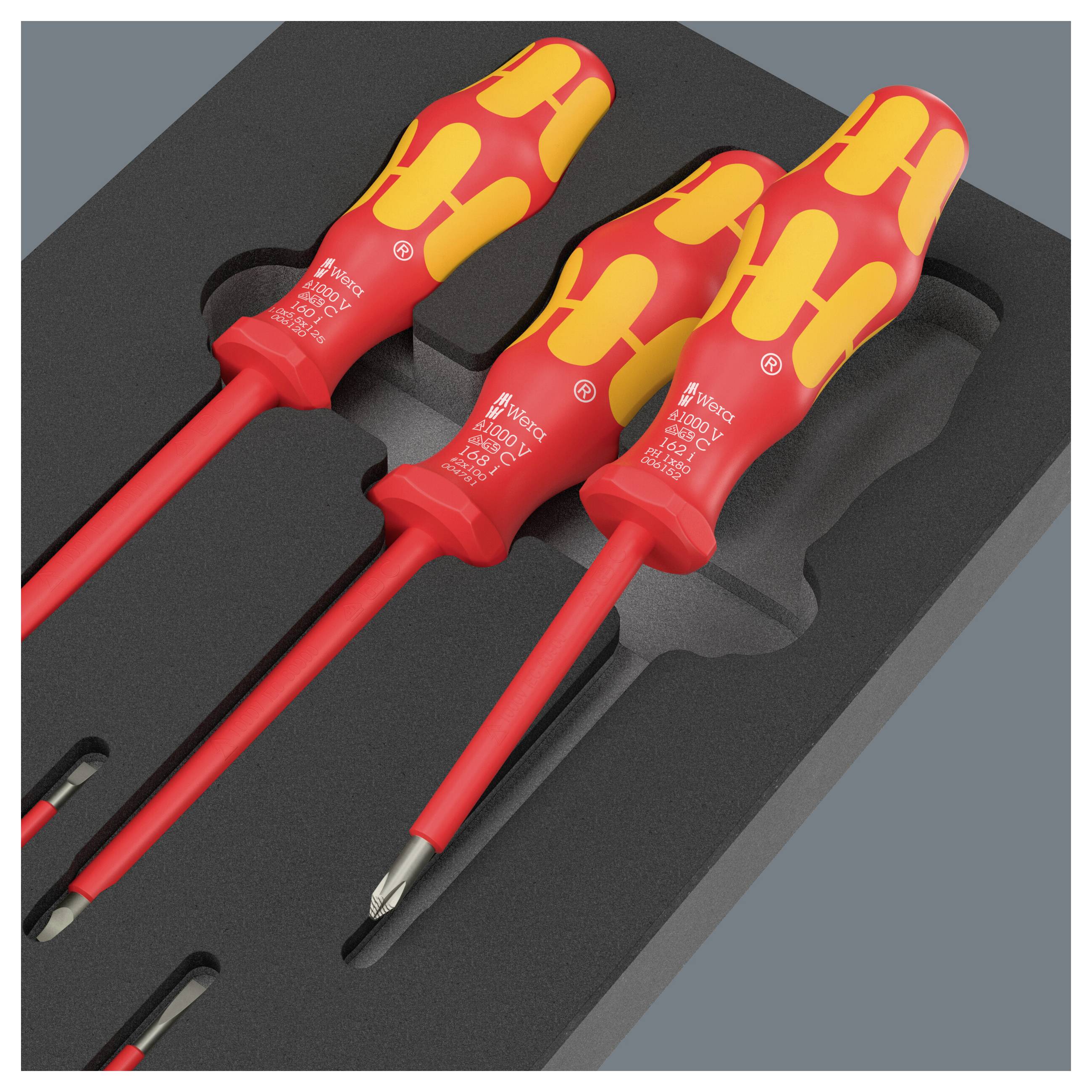 Drei isolierte rot-gelbe Schraubendreher in einem schwarzen Schaumstoffkoffer, gezeigt mit Phillips- und Flachklingenspitzen für elektrotechnische Arbeiten.