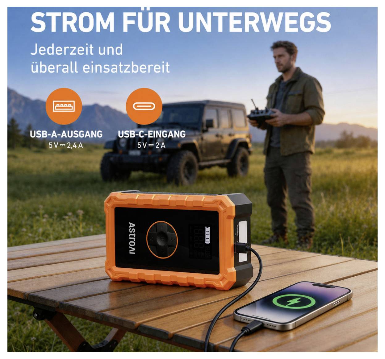 Tragbare Stromstation auf einem Picknicktisch lädt ein Telefon auf, mit deutschem Text „STROM FÜR UNTERWEGS" und USB-A/USB-C-Ausgangsbeschriftungen; Mann und Geländewagen im Hintergrund.