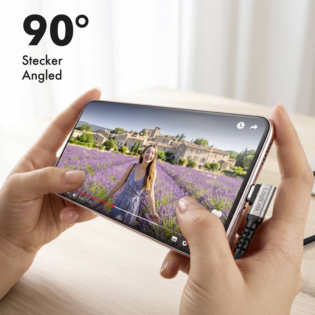 Hände halten ein Smartphone in Querformat, während ein 90° abgewinkeltes Ladekabel eingesteckt ist und ein Video auf dem Bildschirm abgespielt wird.