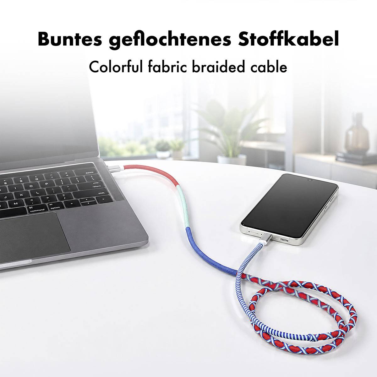 Buntes geflochtenes Ladekabel, das einen Laptop und ein Smartphone auf einem Schreibtisch verbindet, mit dem Text "Buntes geflochtenes Stoffkabel" und "Colorful fabric braided cable".