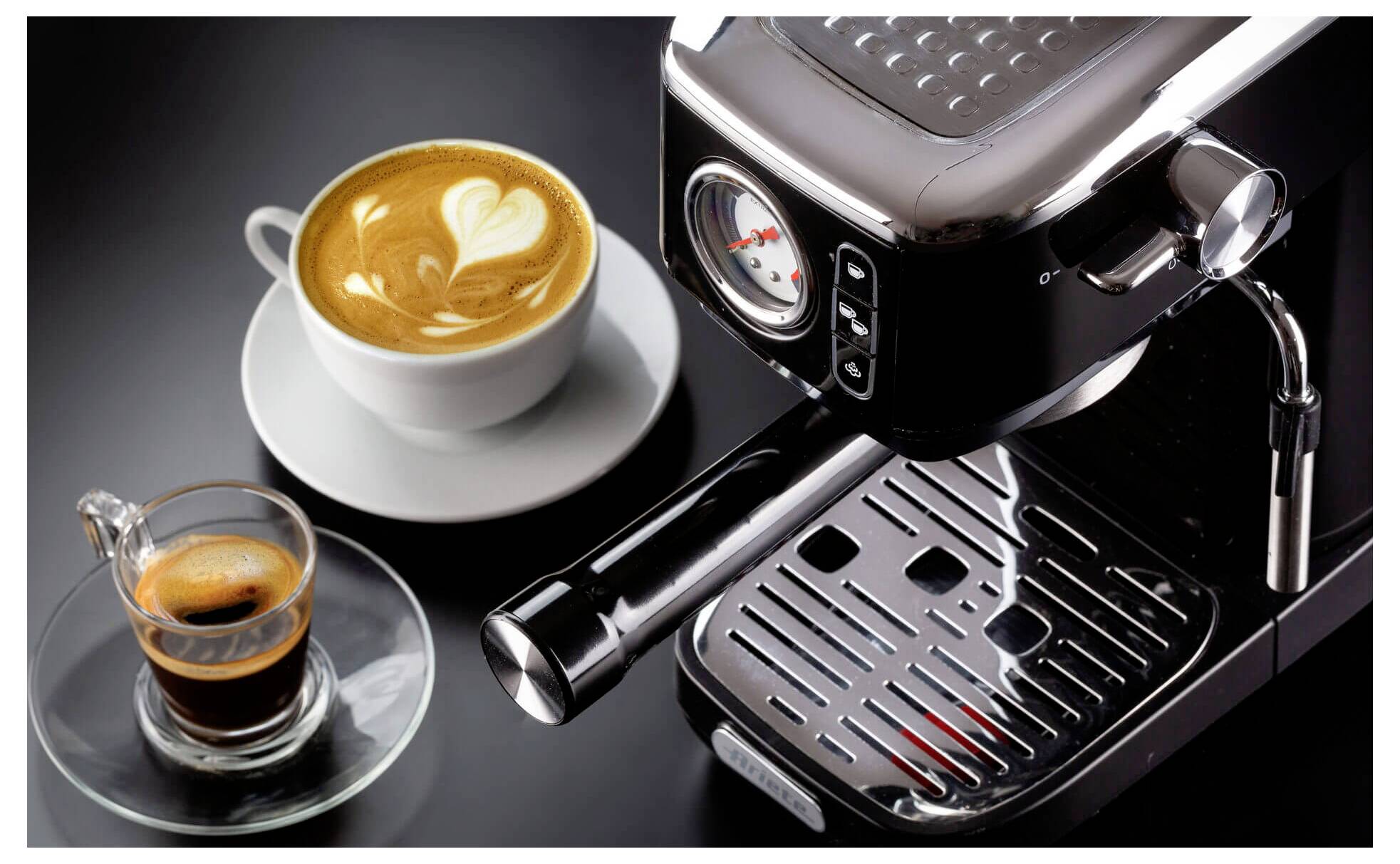 Espressomaschine mit einer Tasse Latte Art und einem kleinen Glas Espresso auf einer Untertasse, auf einer dunklen Arbeitsplatte präsentiert.