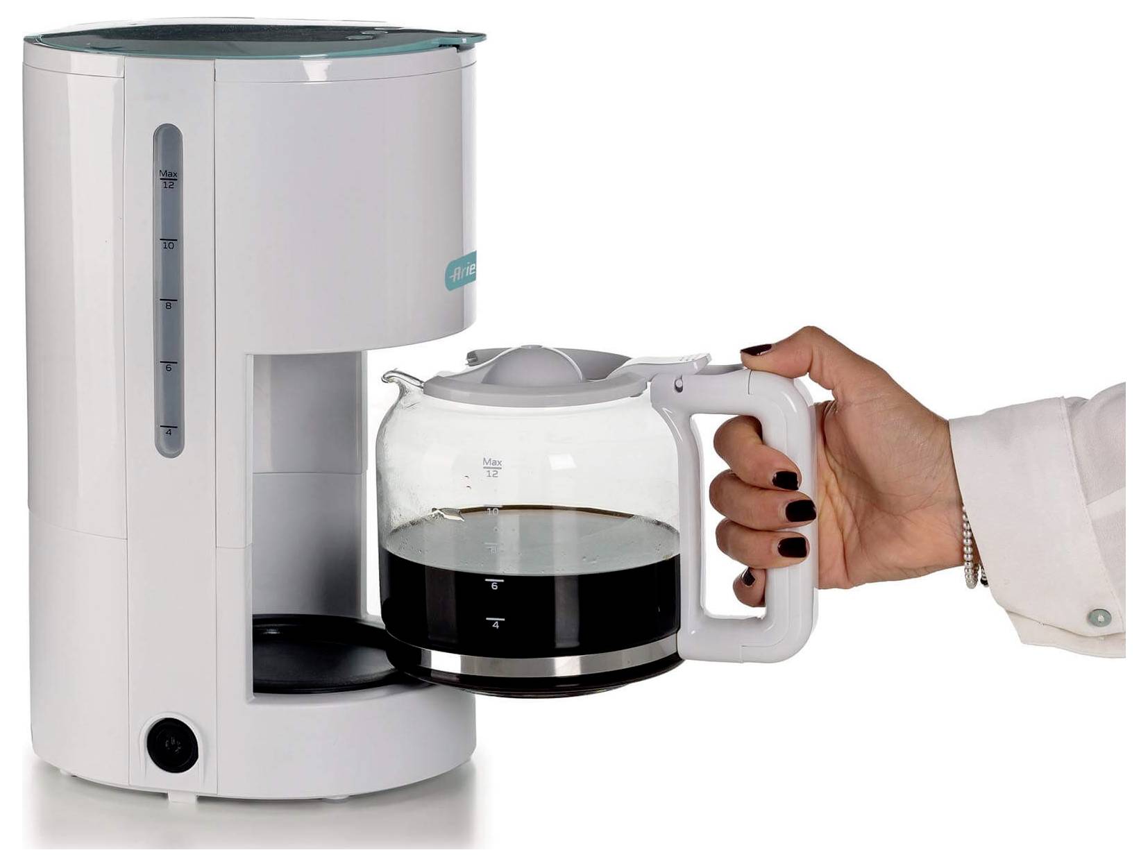 Hand, die eine Glaskaffeekanne unter eine Tropfkaffeemaschine stellt, mit gebrühtem Kaffee, der in der Kanne sichtbar ist.