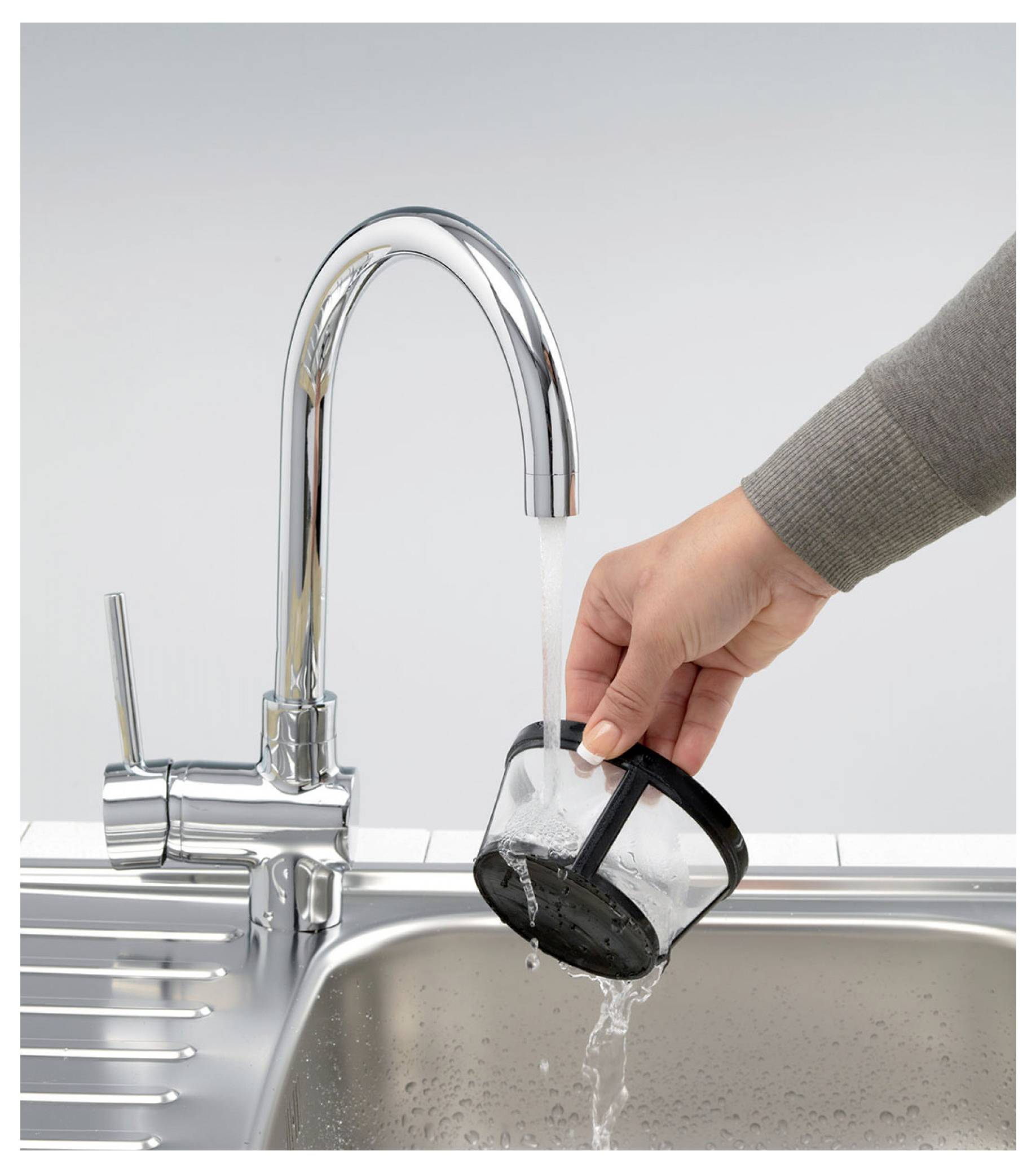 Eine schwarze Maschenfilter-Kaffeefilter unter fließendem Wasser aus einer Küchenarmatur über einem Waschbecken ausspülen.