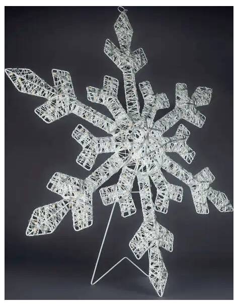 Weiße geflochtene Schneeflockenornament mit sechszackigen Ästen auf dunklem Hintergrund, hängend an einem dünnen Ständer aus Draht.