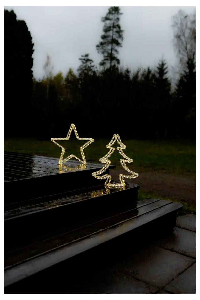 Beleuchtete Stern- und Weihnachtsbaumdekorationen auf dunklen Außentreppen in einem Park in der Abenddämmerung.