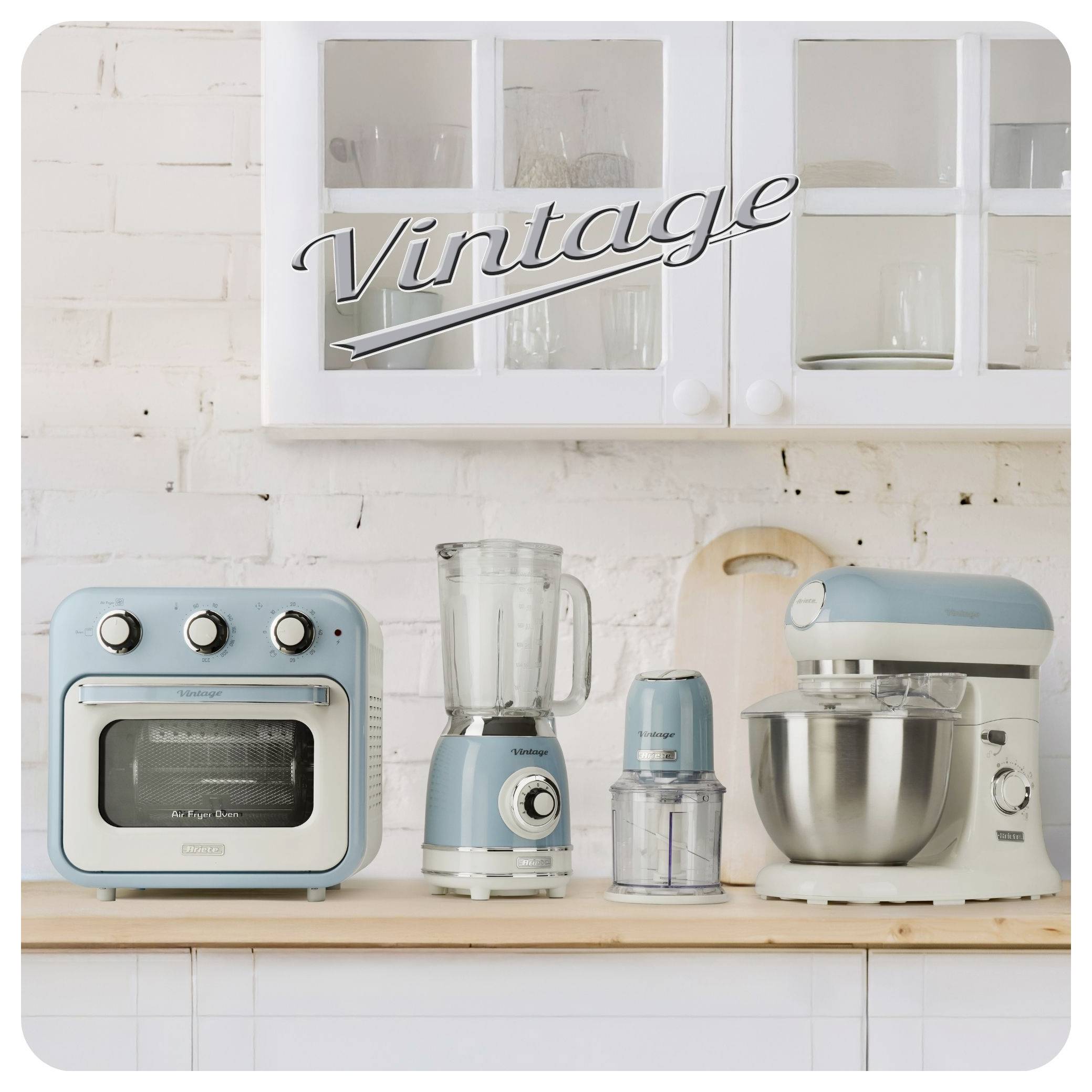 Vintage-Küchengeräte im Blauton in einer Reihe auf einer Arbeitsplatte unter einem Schrank aufgestellt, darunter ein Toasterofen, ein Standmixer, eine Kaffeemühle und eine Küchenmaschine.