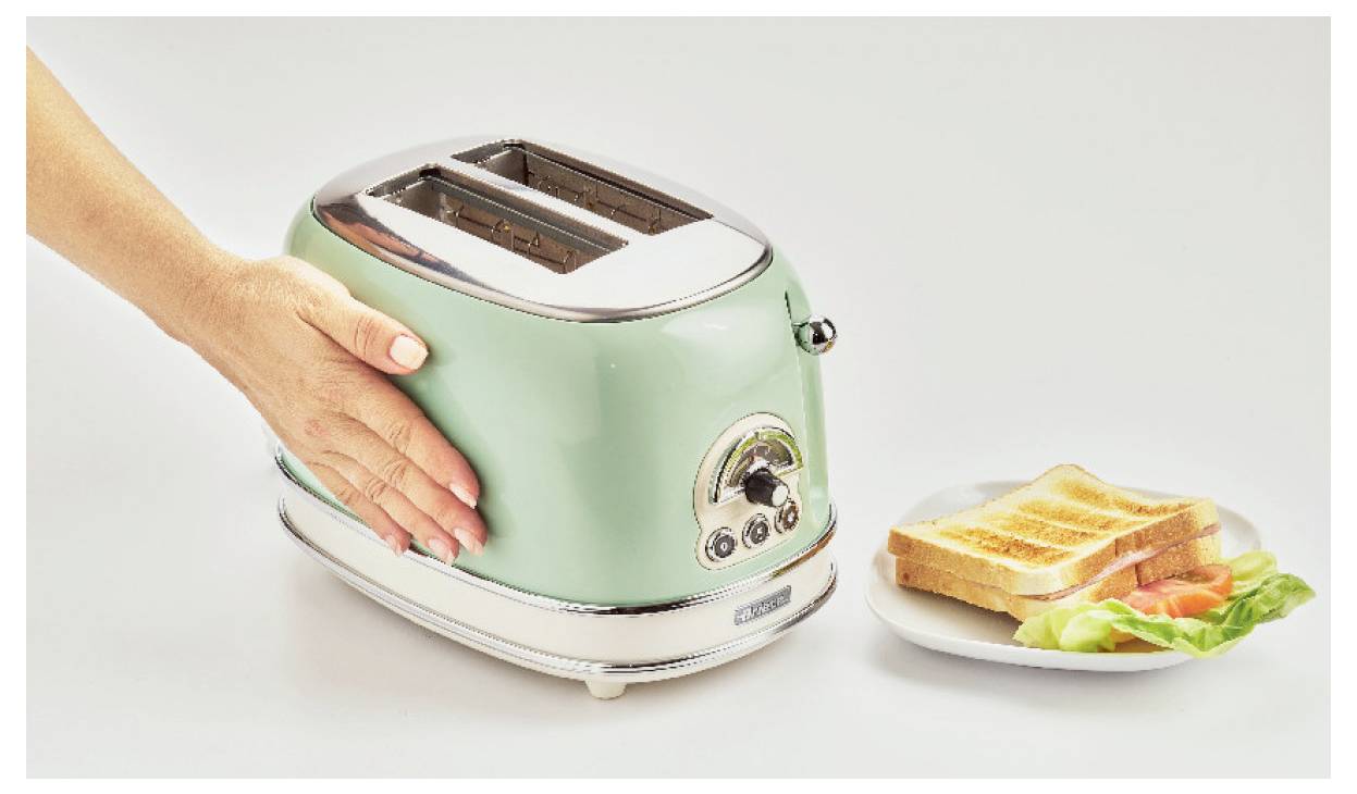 Eine Hand drückt auf einen mintgrünen Toaster neben einem Teller mit getostetem Brot und Salat, was die Frühstückszubereitung zeigt.
