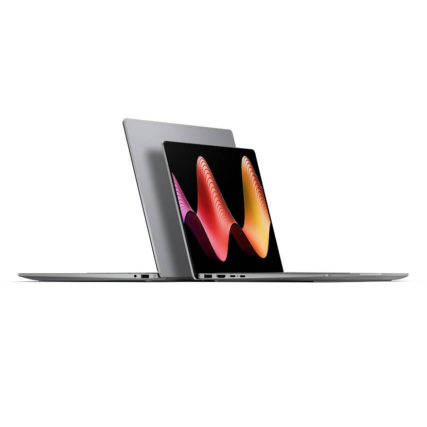 Zwei schlanke Laptops, von der Seite gezeigt, einer offen vor einem größeren geschlossenen Laptop, auf dem Bildschirm eine bunte abstrakte Welle angezeigt.