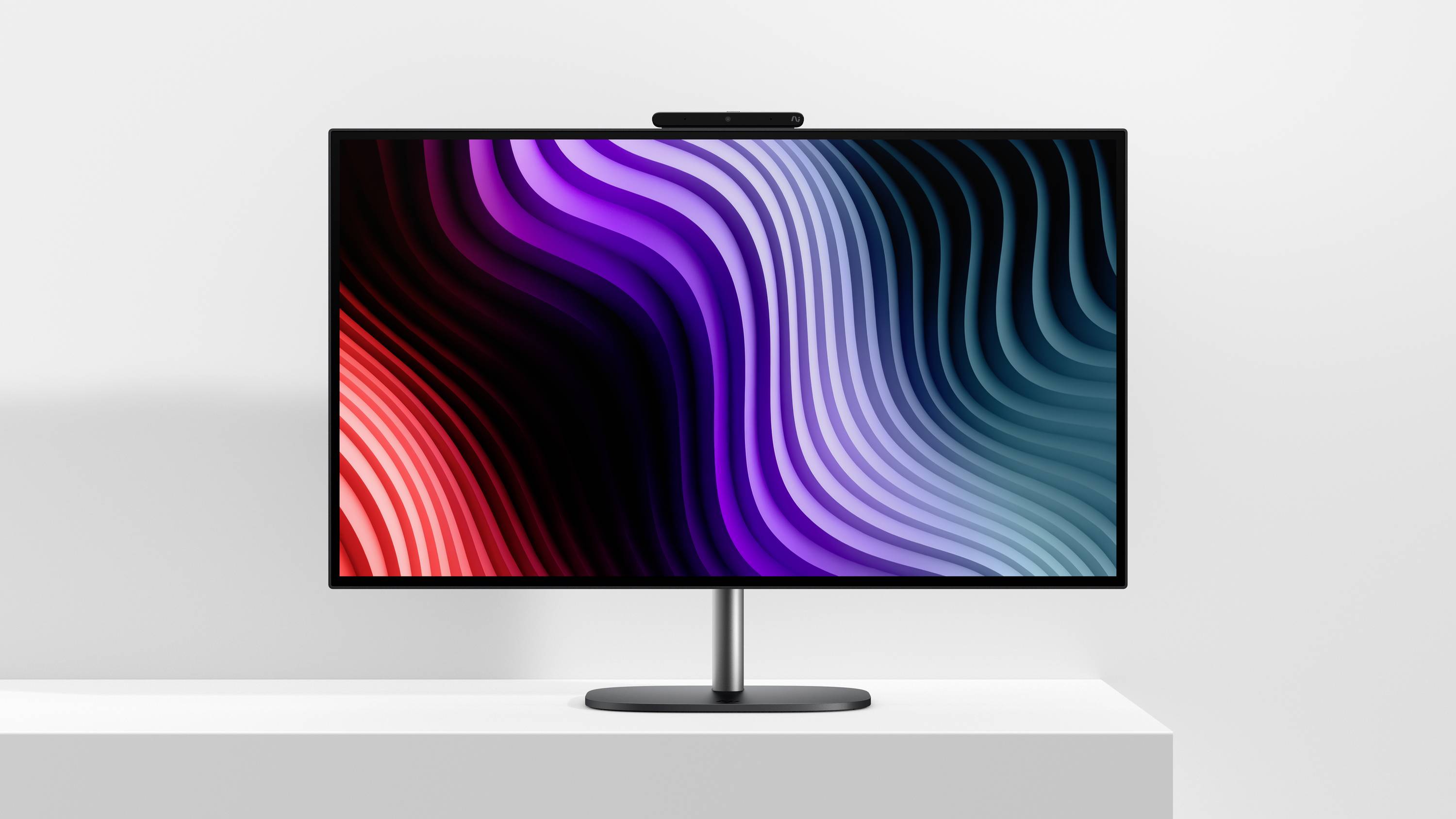 Flachbildschirm-Monitor auf einem weißen Schreibtisch, auf dem farbenfrohe wellenförmige abstrakte Linien in Rot, Violett und Blau angezeigt werden.