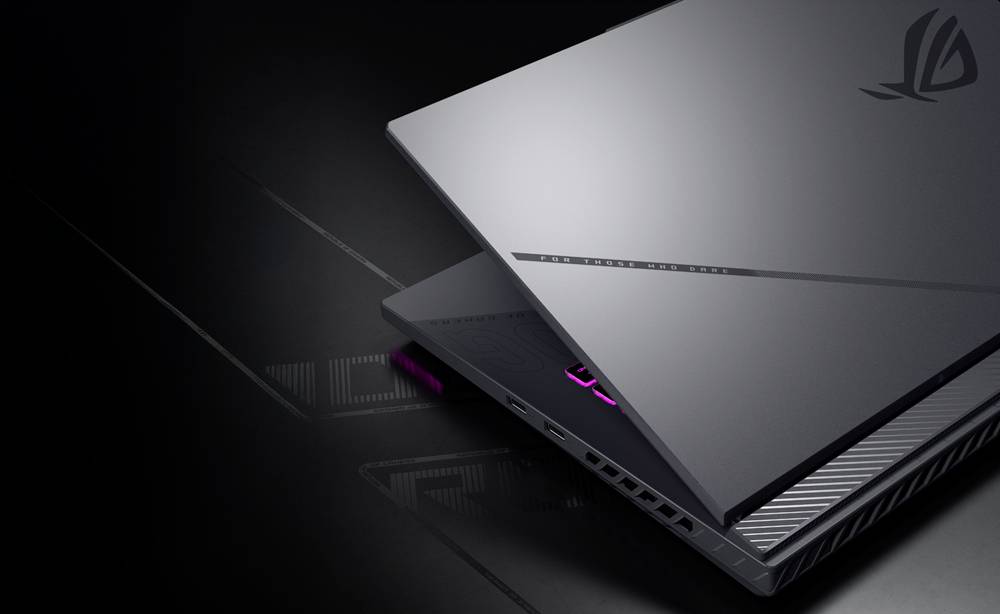 Nahaufnahme eines silbernen ASUS ROG Gaming-Laptops, der teilweise geöffnet ist und eine dunkle Tastatur mit rosa Hintergrundbeleuchtung und kantigen Lüftungsschlitzen zeigt.