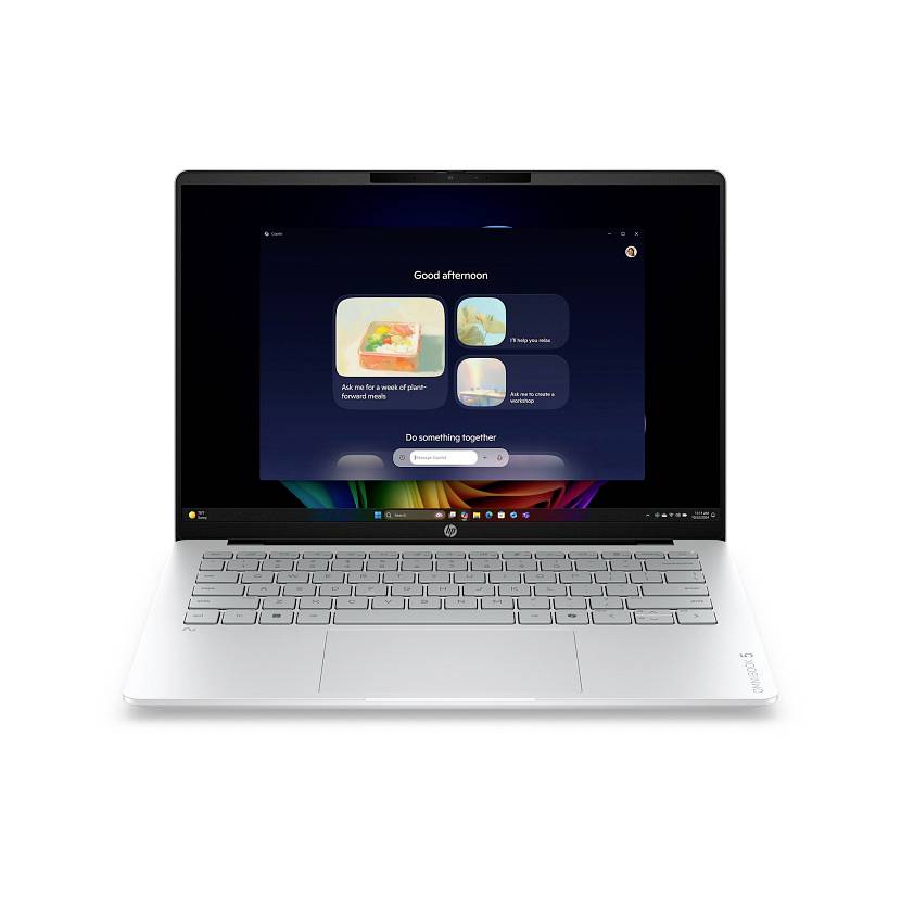 Ein silberner Laptop, der auf weißem Hintergrund offen ist und einen dunklen Willkommensbildschirm mit der Aufschrift "Guten Nachmittag" und Kacheln mit App-Vorschlägen anzeigt.