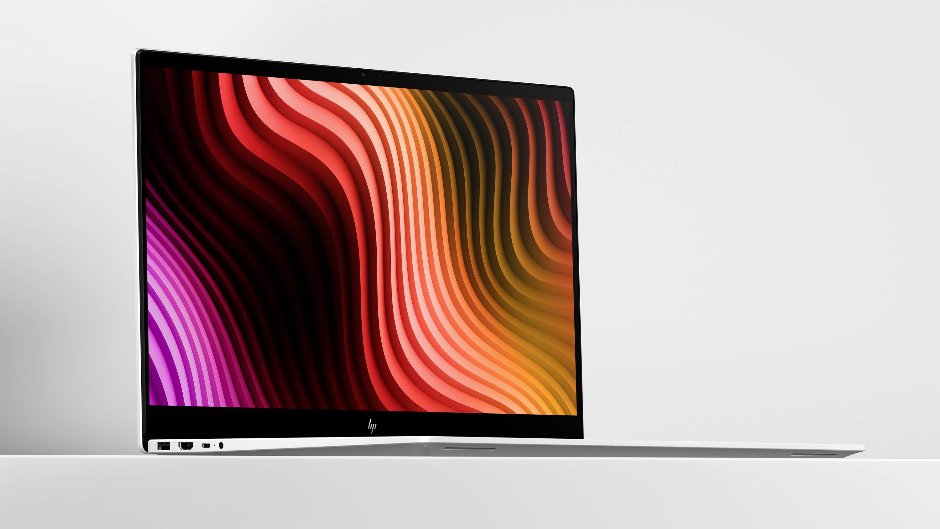 Schlanker silberner HP-Laptop, geöffnet mit buntem, welligem abstraktem Hintergrund auf dem Bildschirm, von der Seite auf hellem Hintergrund betrachtet.