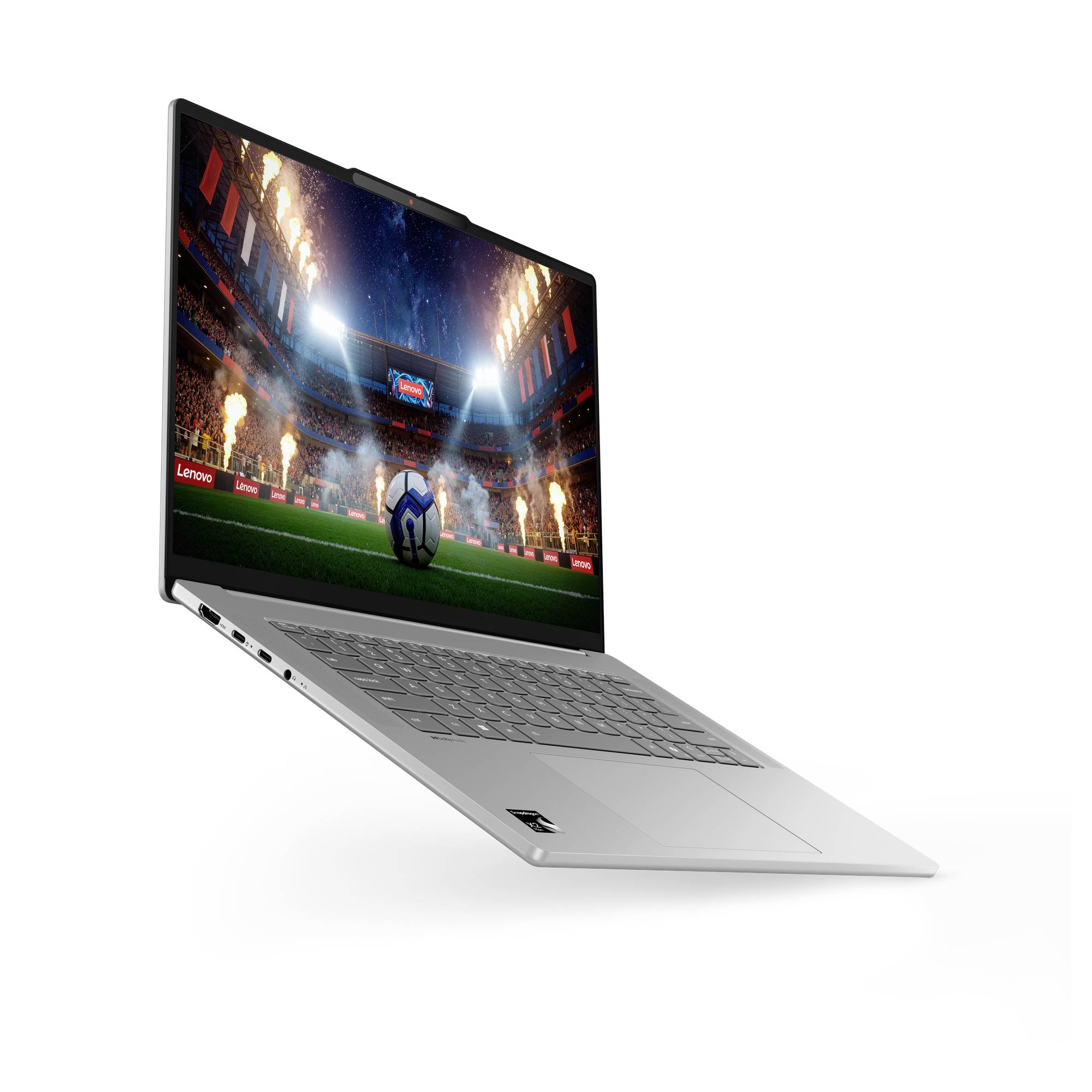 Silberner Laptop, der in einem Winkel aufgeklappt dargestellt ist, mit einer Fußballstadion-Szene auf dem Display, einem Ball auf dem Spielfeld und hellen Leuchten über ihm.