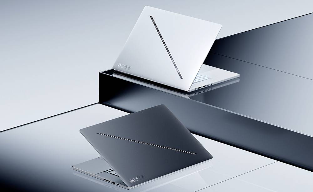 Zwei geschlossene Laptops, einer silberfarben und einer dunkelgrau, auf reflektierenden gestuften Plattformen vor einem minimalistischen grauen Hintergrund ausgestellt.